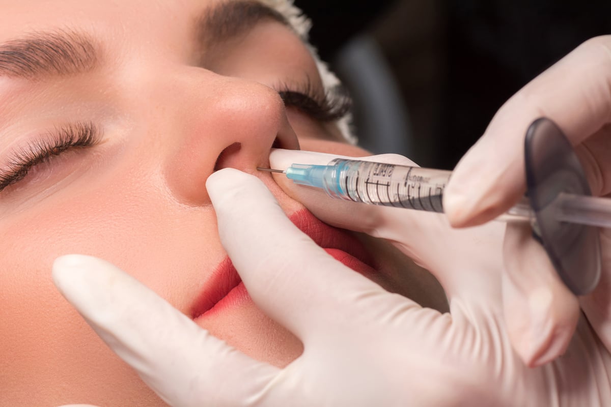 Injection rhinoplasty. Woman getting cosmetic injection of botulinum to nose.